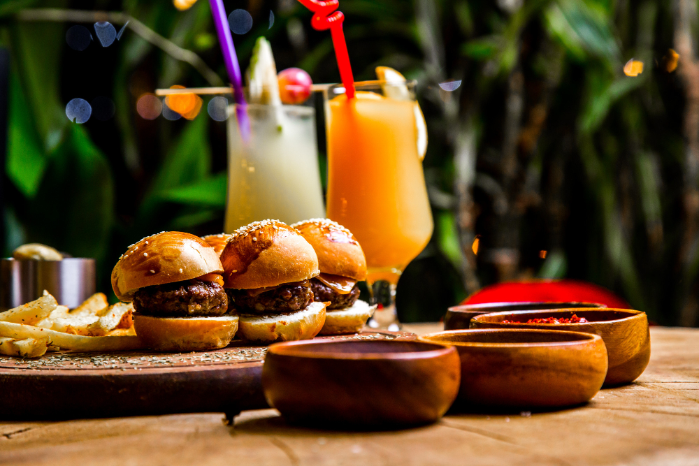 Burgers with french fries, drinks, and wooden bowls with sauce