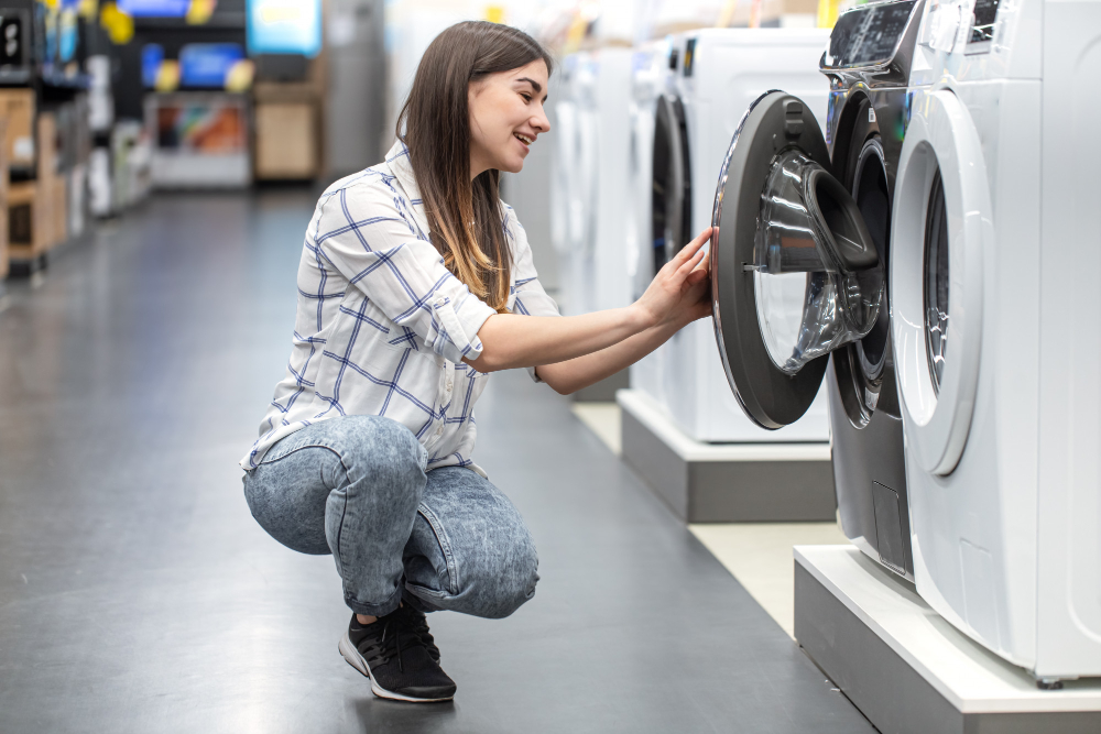 Woman examining washing machine in appliance store